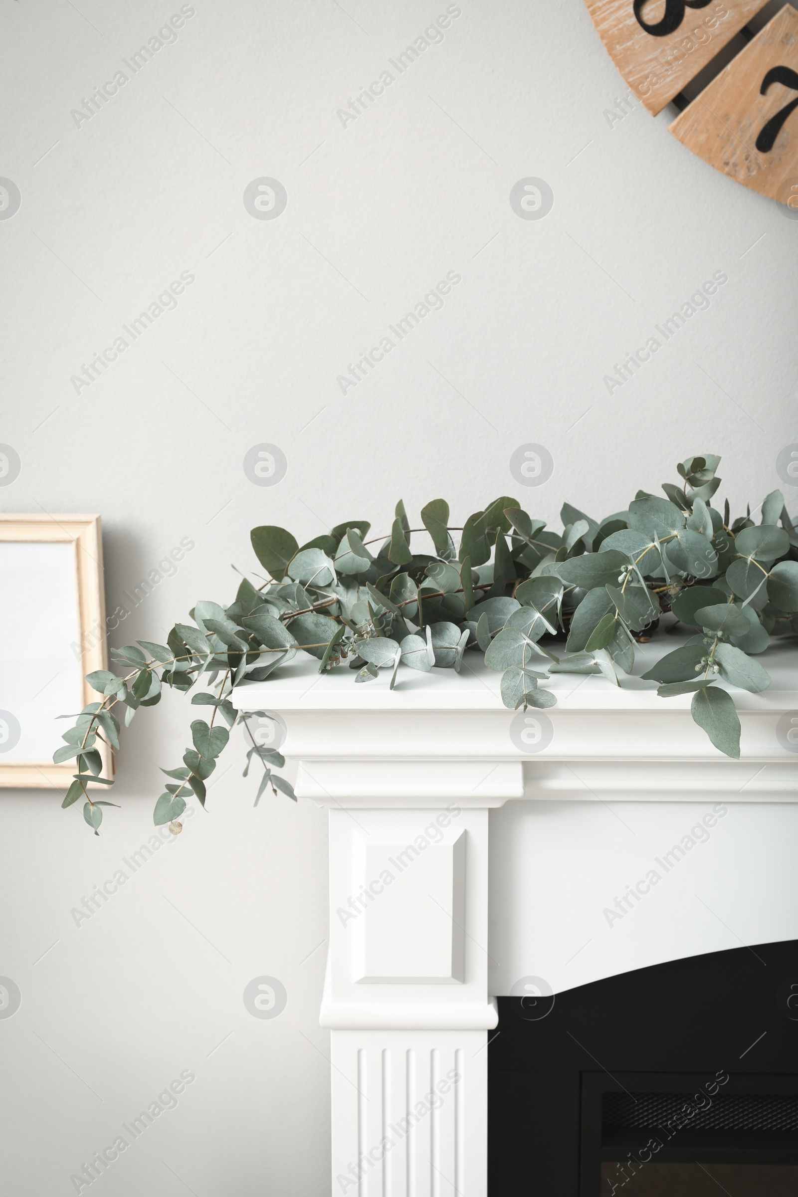 Photo of Beautiful garland with eucalyptus branches on mantelpiece in room