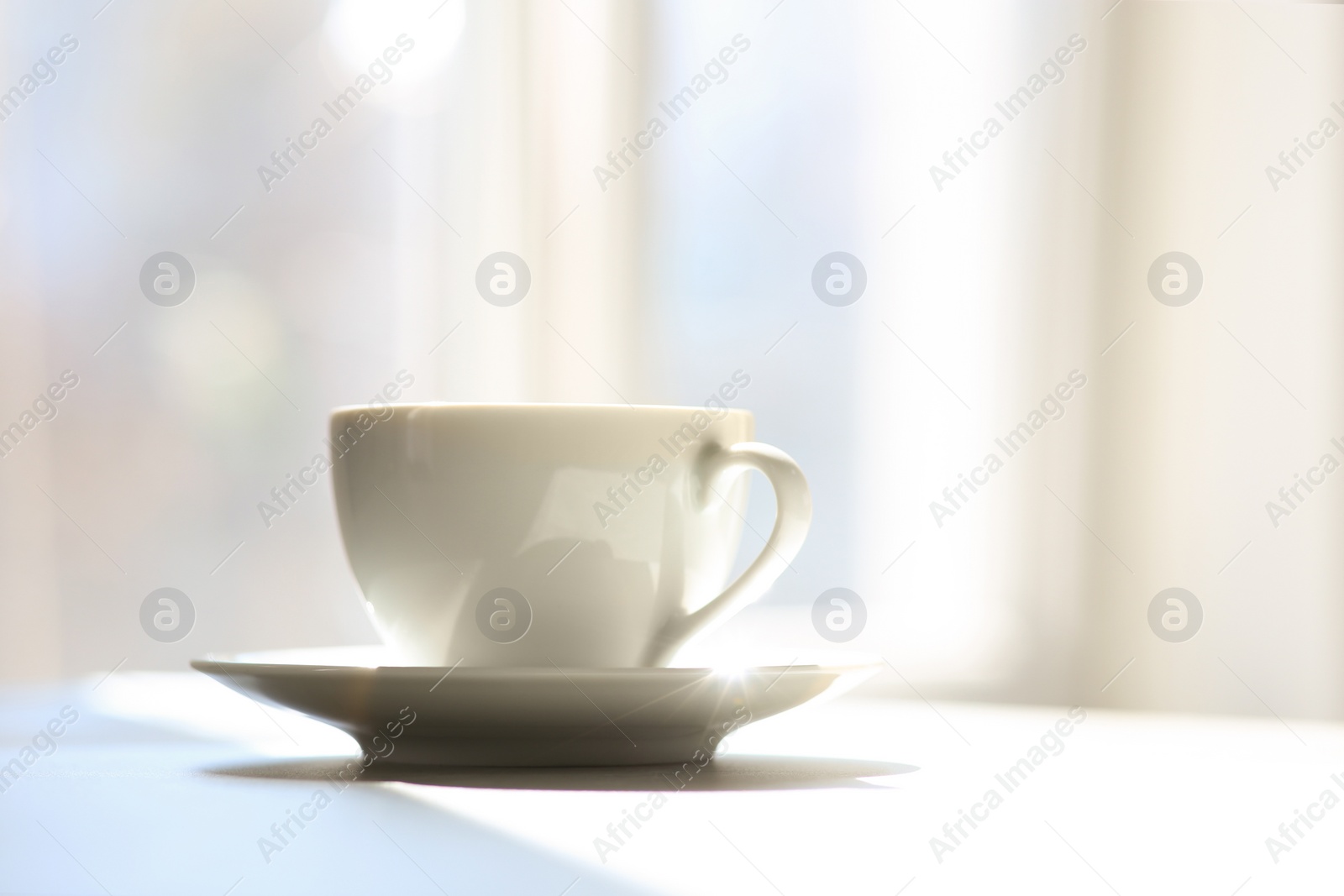 Photo of Cup of delicious coffee on sunlit table, space for text. Good morning