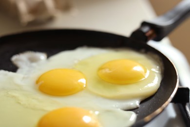 Photo of Cooking tasty eggs on frying pan, closeup