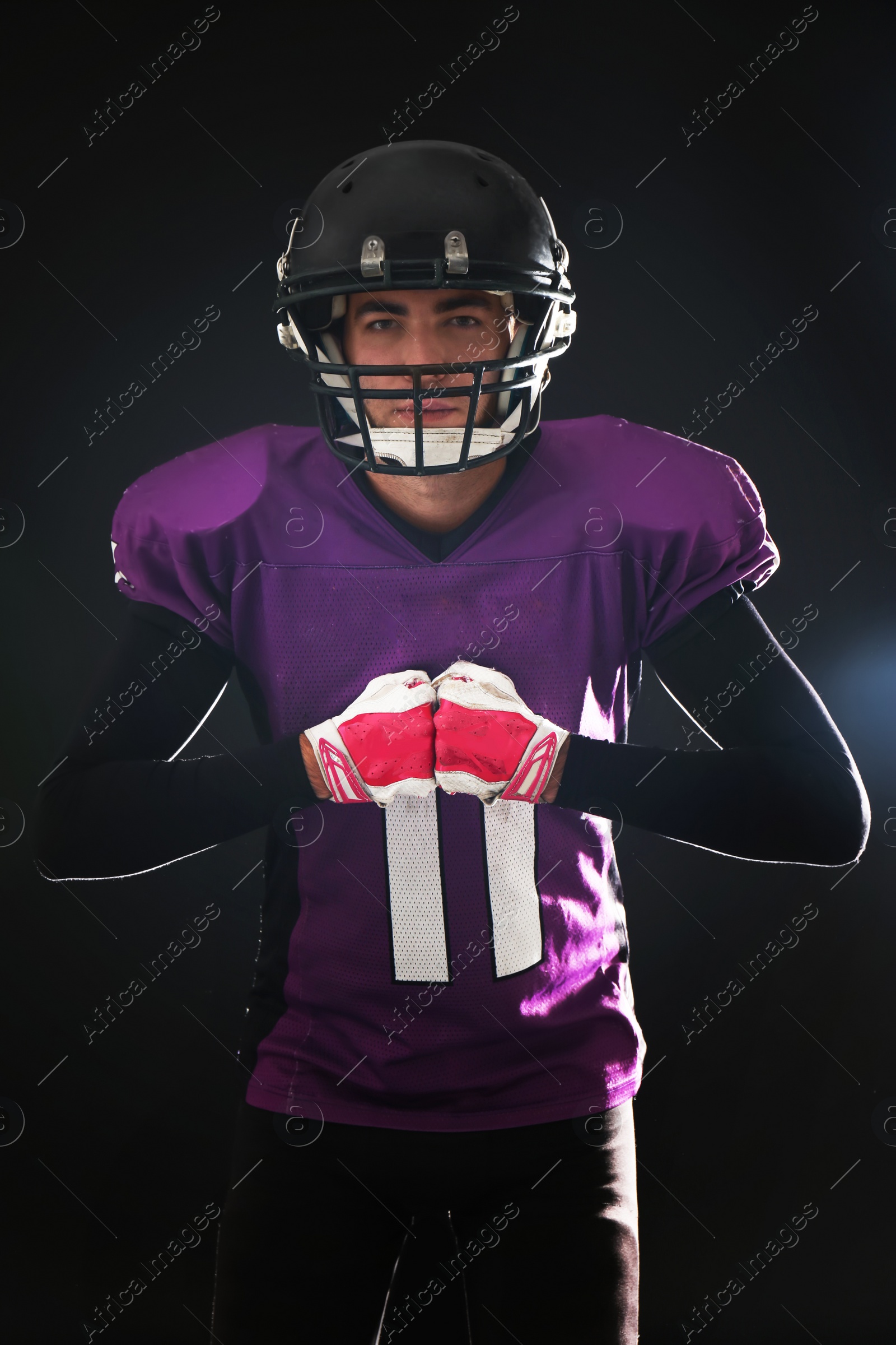 Photo of American football player wearing uniform on dark background