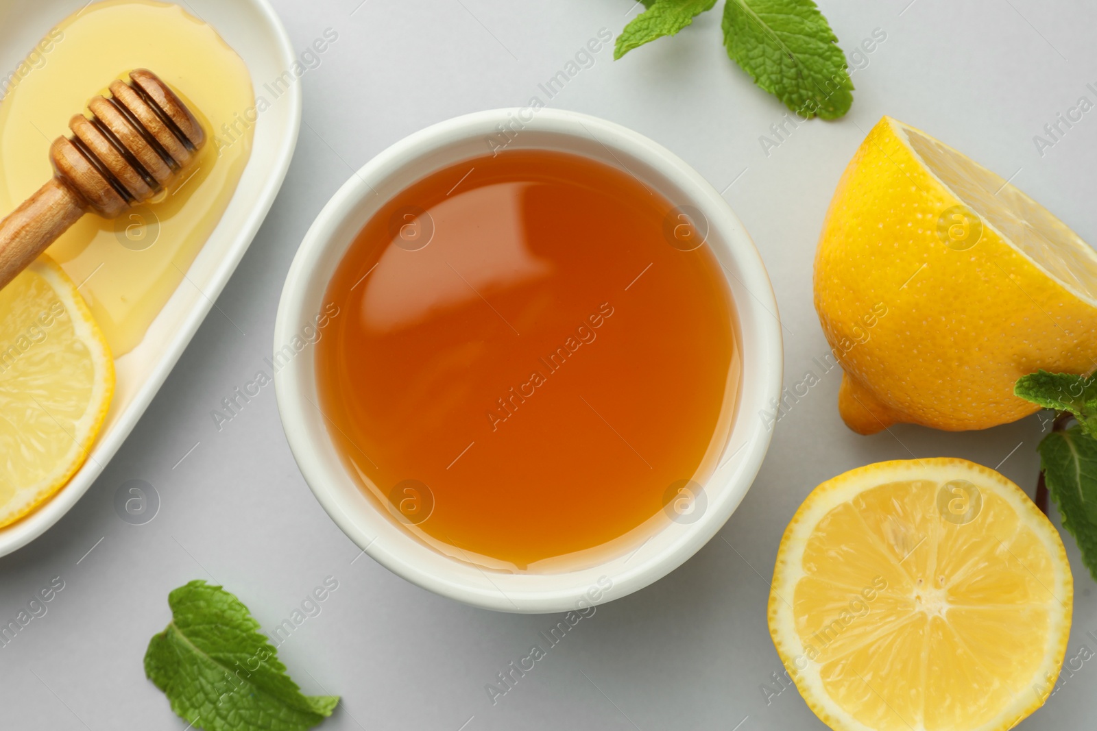 Photo of Sweet honey and fresh lemon on white table, flat lay