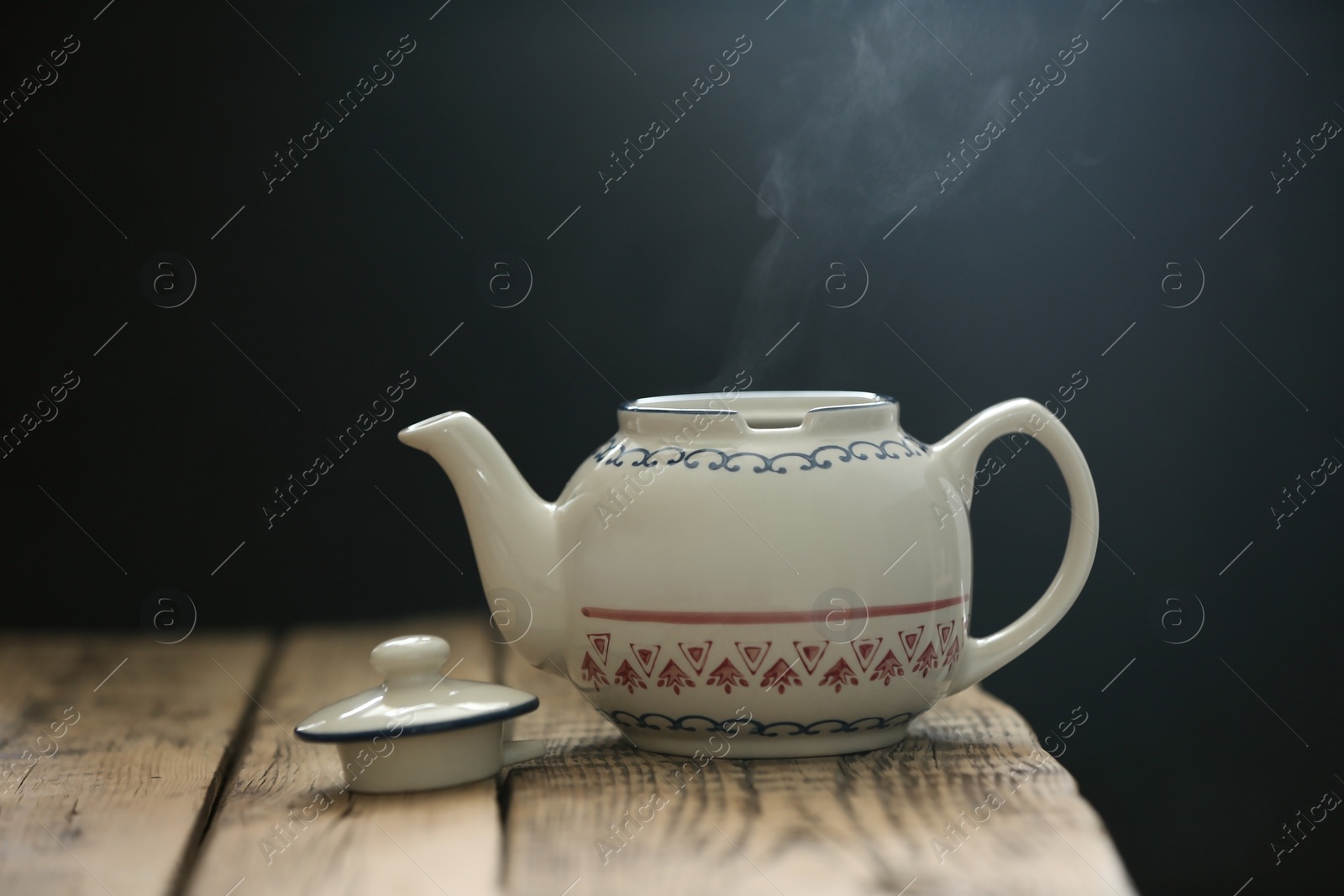 Photo of Porcelain tea pot on wooden table against gray background