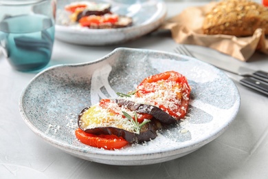 Photo of Baked eggplant with tomatoes, cheese and rosemary on table