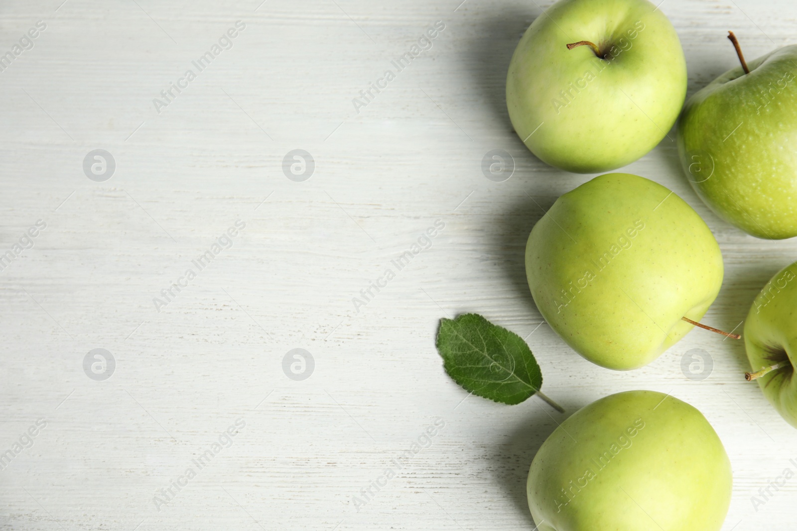 Photo of Flat lay composition of fresh ripe green apples on white wooden table, space for text