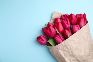 Photo of Bouquet of beautiful tulips on light blue background, top view. Space for text