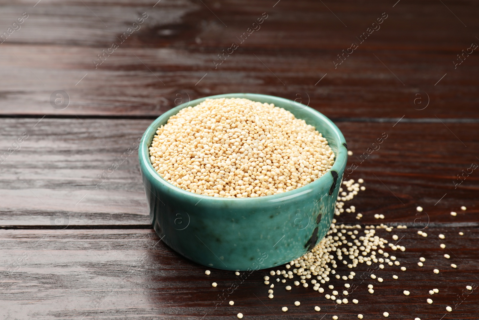 Photo of Dry quinoa seeds in bowl on wooden table