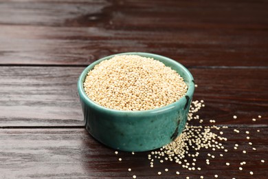 Photo of Dry quinoa seeds in bowl on wooden table