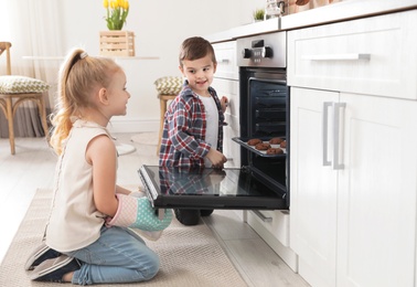 Photo of Little kids baking cookies in oven at home