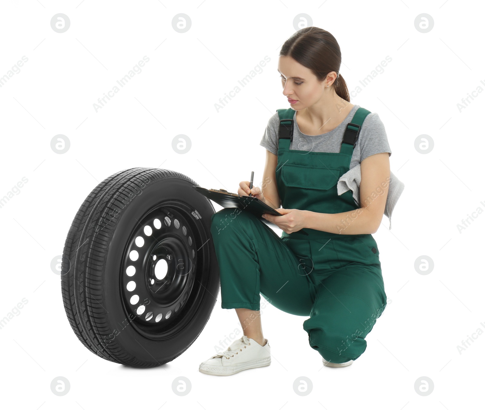 Photo of Professional auto mechanic with wheel and clipboard on white background