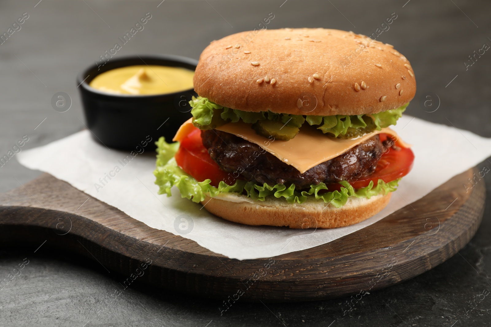 Photo of Tasty hamburger with patty and sauce on black table, closeup