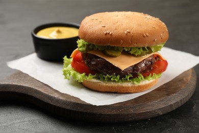 Photo of Tasty hamburger with patty and sauce on black table, closeup