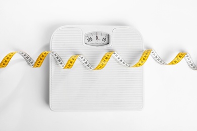 Photo of Measuring tape and scales on white background, top view. Concept of weight loss