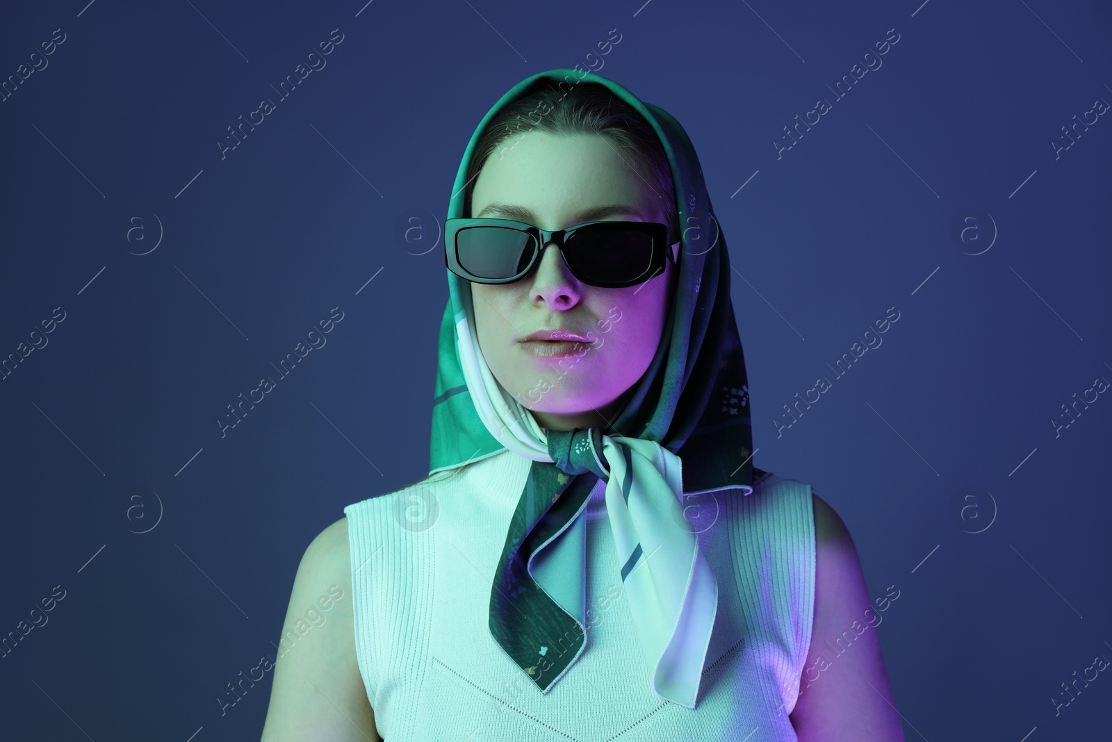 Photo of Portrait of beautiful young woman with sunglasses on color background with neon lights