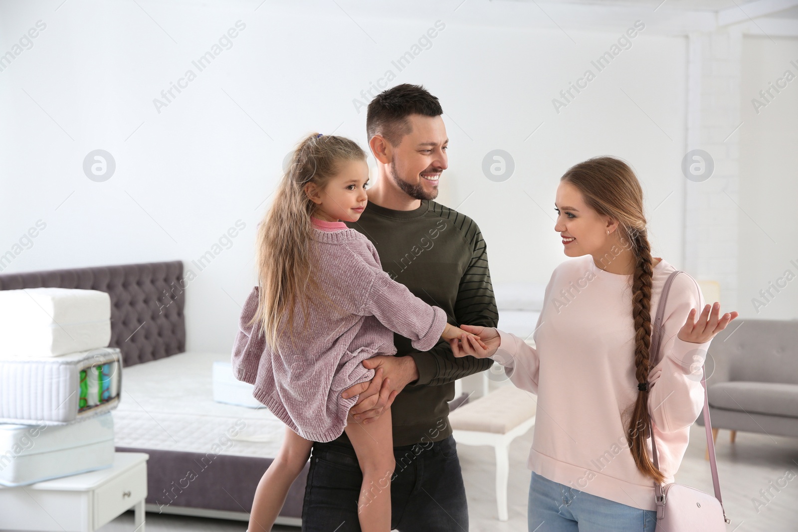 Photo of Happy family looking for mattress in furniture store