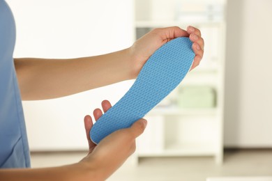 Photo of Female orthopedist holding insole in hospital, closeup