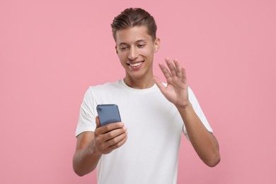 Photo of Happy man having videochat by smartphone on pink background
