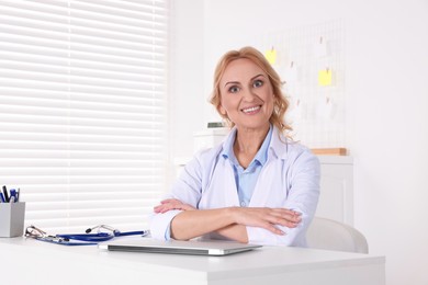 Doctor with laptop at workplace in clinic. Online medicine concept