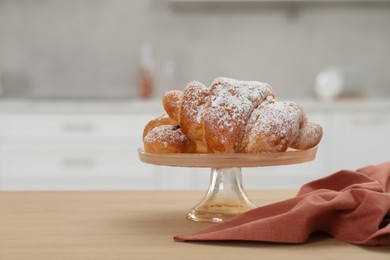 Stand with delicious croissants and napkin on table in kitchen, space for text