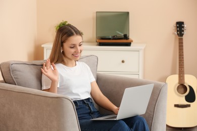 Teenage girl using laptop for video chat in room