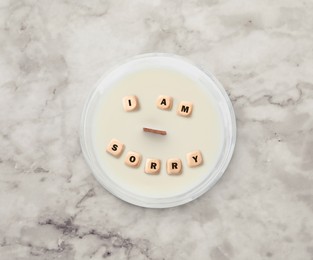 Image of Apology. Phrase I Am Sorry of wooden cubes in candle on white marble table, top view