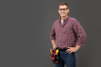 Photo of Handsome carpenter with tool belt on dark background. Space for text
