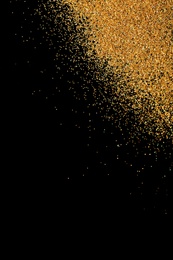 Photo of Gold glitter on black background, top view with space for text