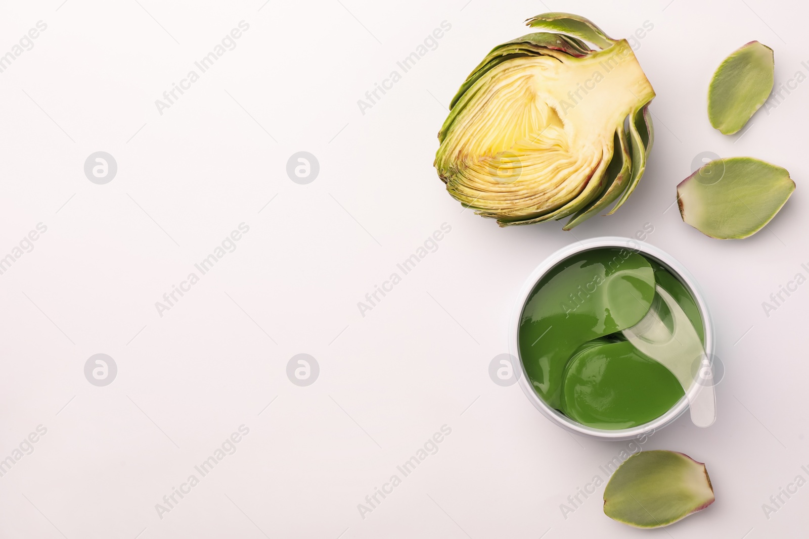 Photo of Package of under eye patches and artichokes on white background, top view. Cosmetic product