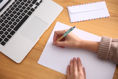 Photo of Woman writing letter at wooden table, above view