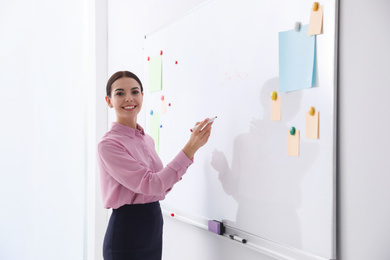 Young teacher writing on whiteboard in classroom