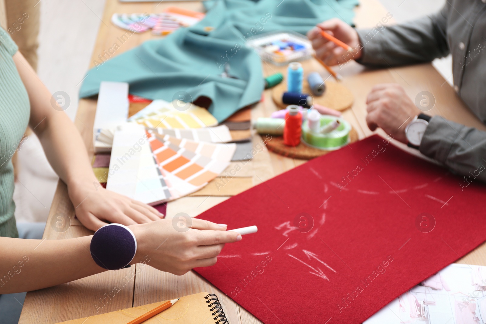 Photo of Fashion designers creating new clothes at table in studio, closeup