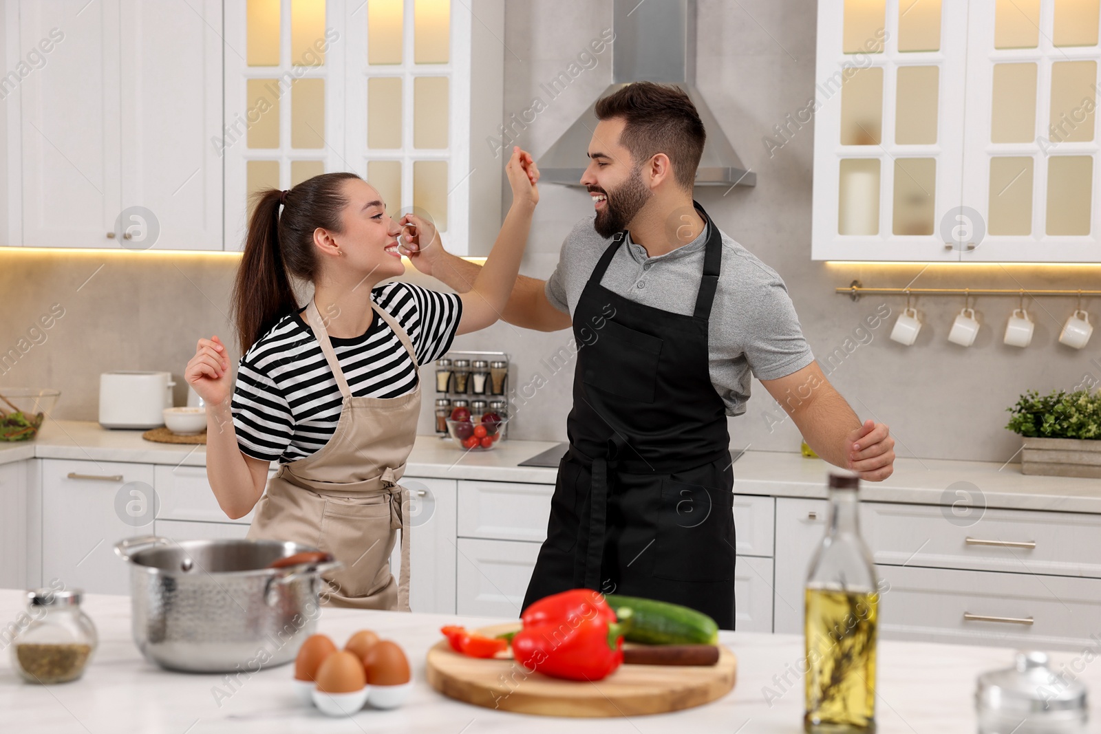 Photo of Happy lovely couple dancing together while cooking in kitchen