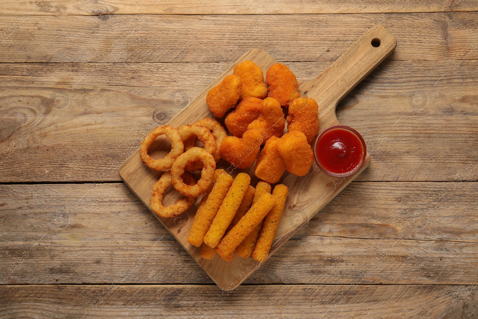 Photo of Board with tasty ketchup and different snacks on wooden table, top view