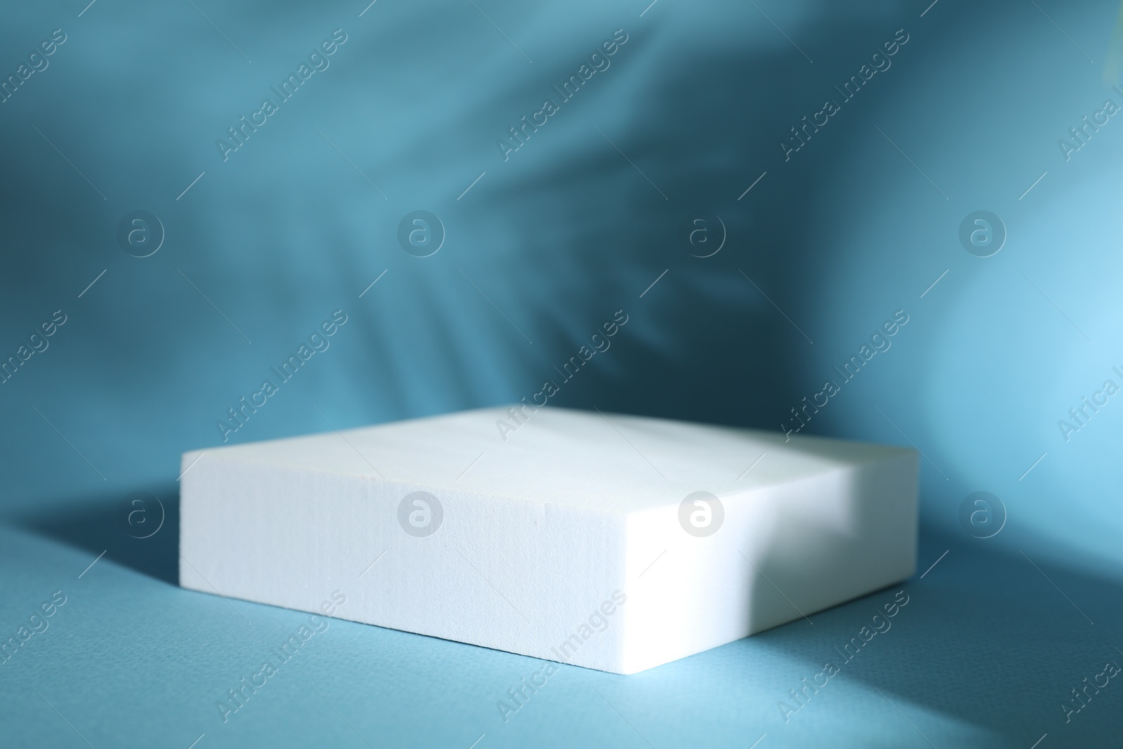 Photo of Presentation of product. Podium and shadows on light blue background. Space for text