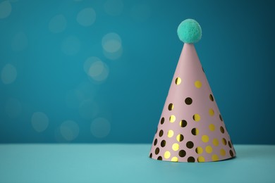 Photo of Pink party hat on light blue background, space for text