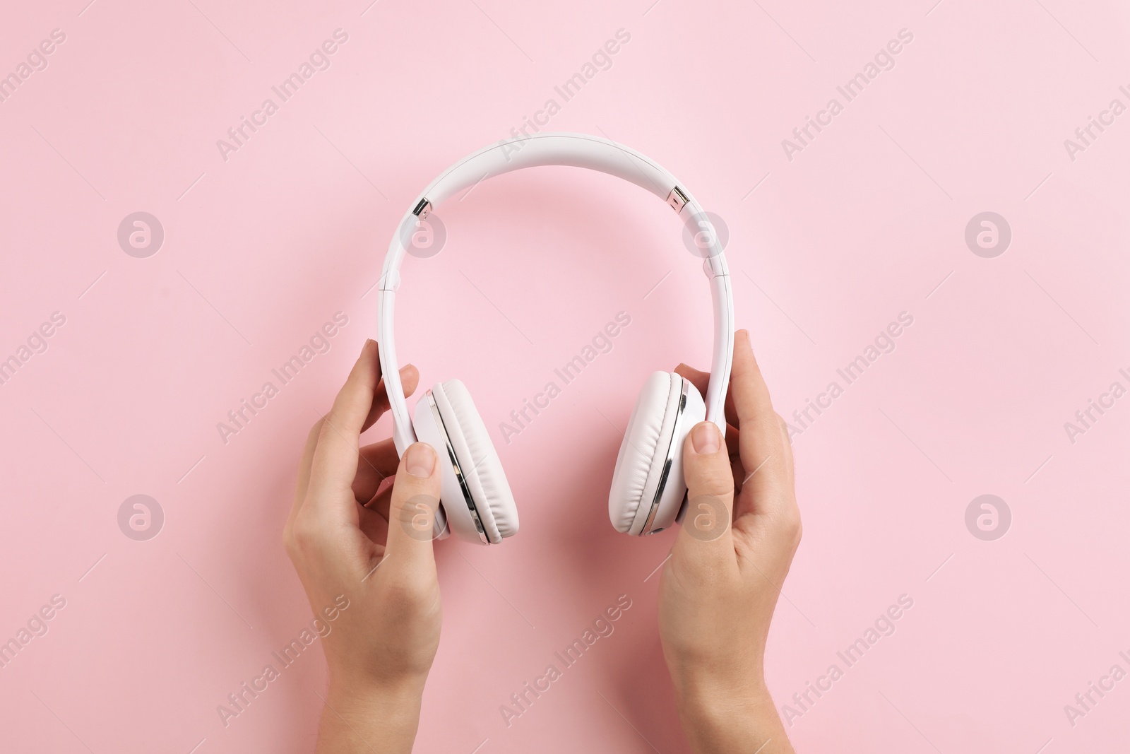 Photo of Woman holding headphones on color background, top view