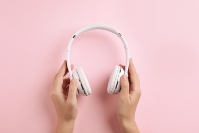 Photo of Woman holding headphones on color background, top view