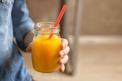 Woman holding jar of orange juice, closeup