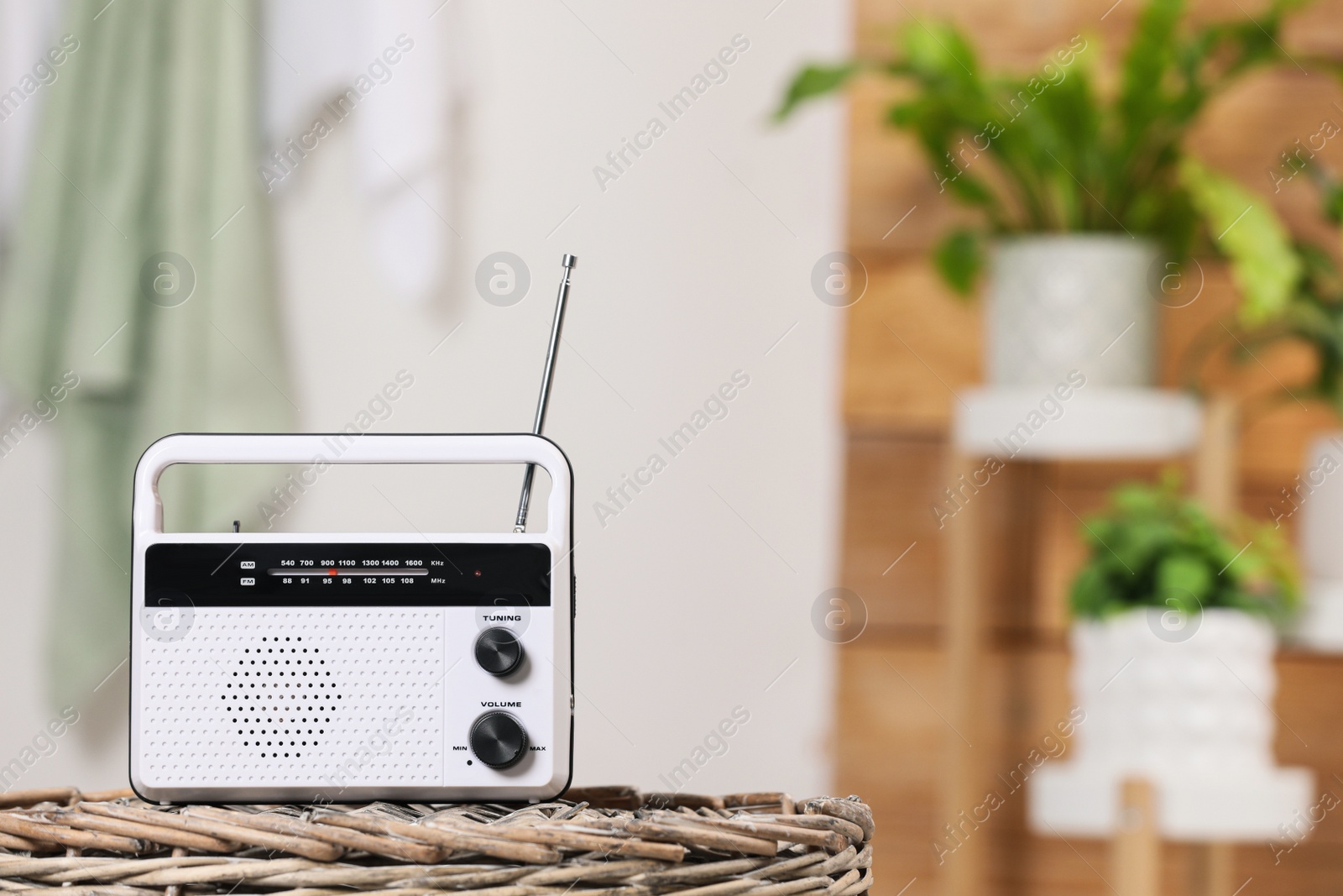 Photo of Stylish white radio on wicker stand indoors, space for text
