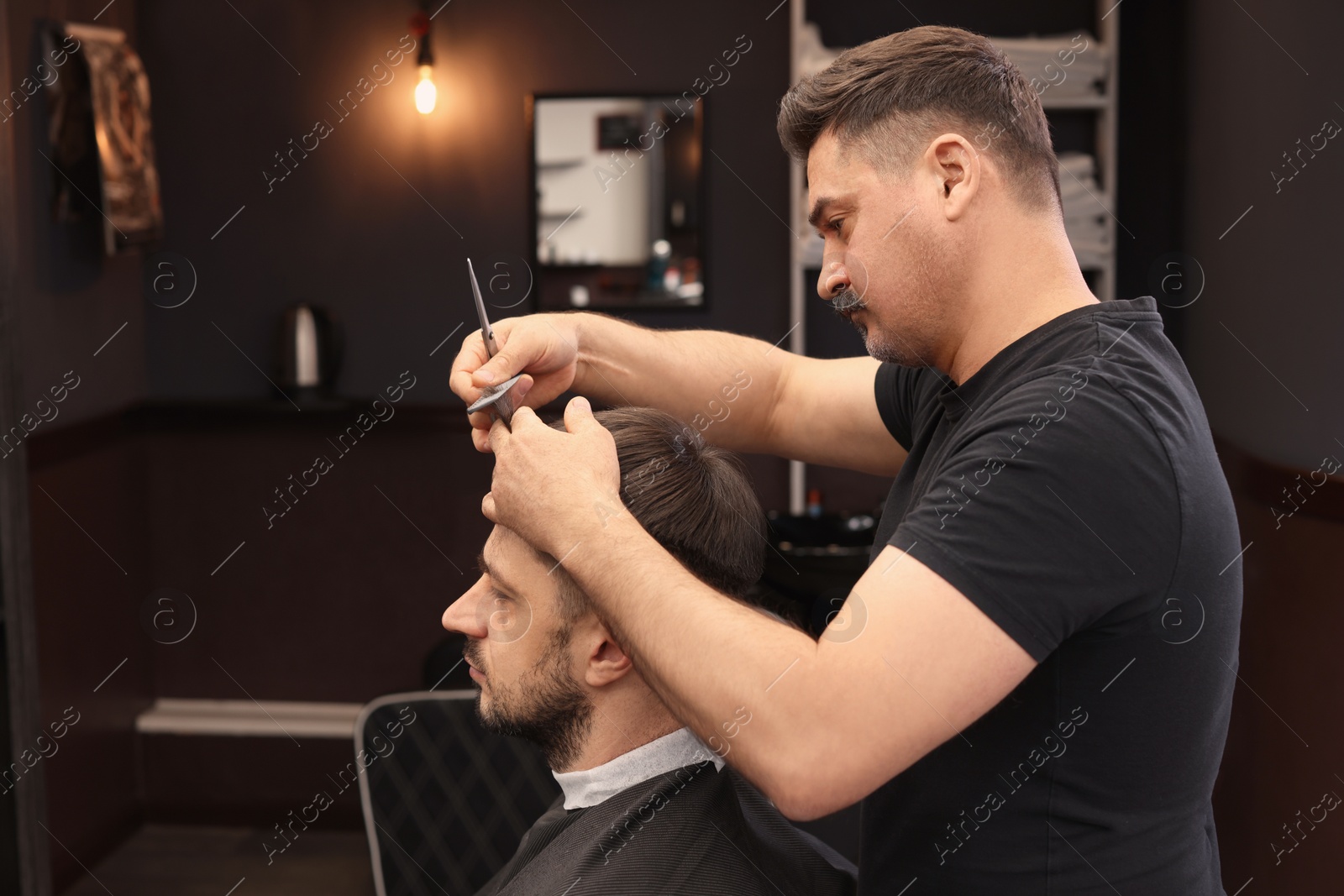 Photo of Professional hairdresser cutting man's hair in barbershop