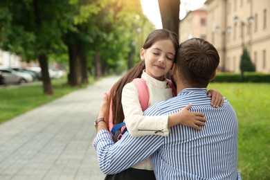 Photo of Father hugging his little daughter before school outdoors