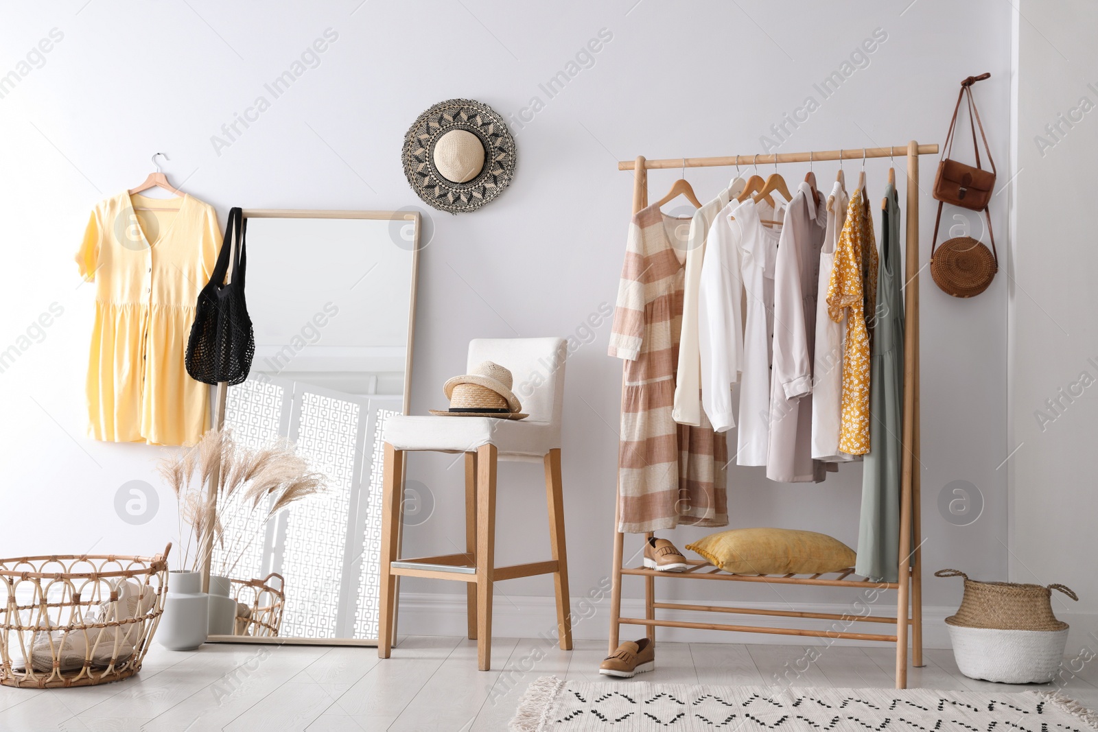 Photo of Rack with stylish women's clothes and mirror indoors. Interior design