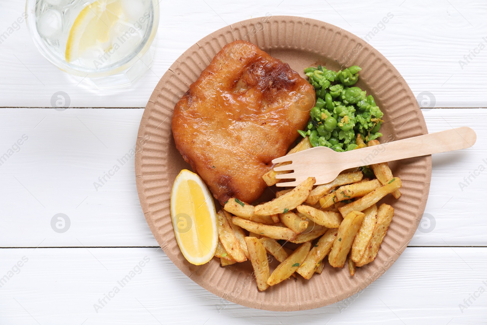 Photo of Tasty fish, chips, peas and lemon on white wooden table, top view. Space for text