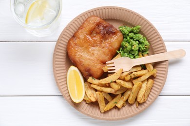 Photo of Tasty fish, chips, peas and lemon on white wooden table, top view. Space for text