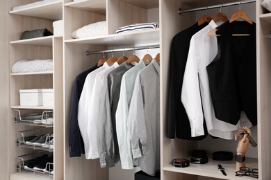 Photo of Stylish clothes, shoes and home stuff in large wardrobe closet