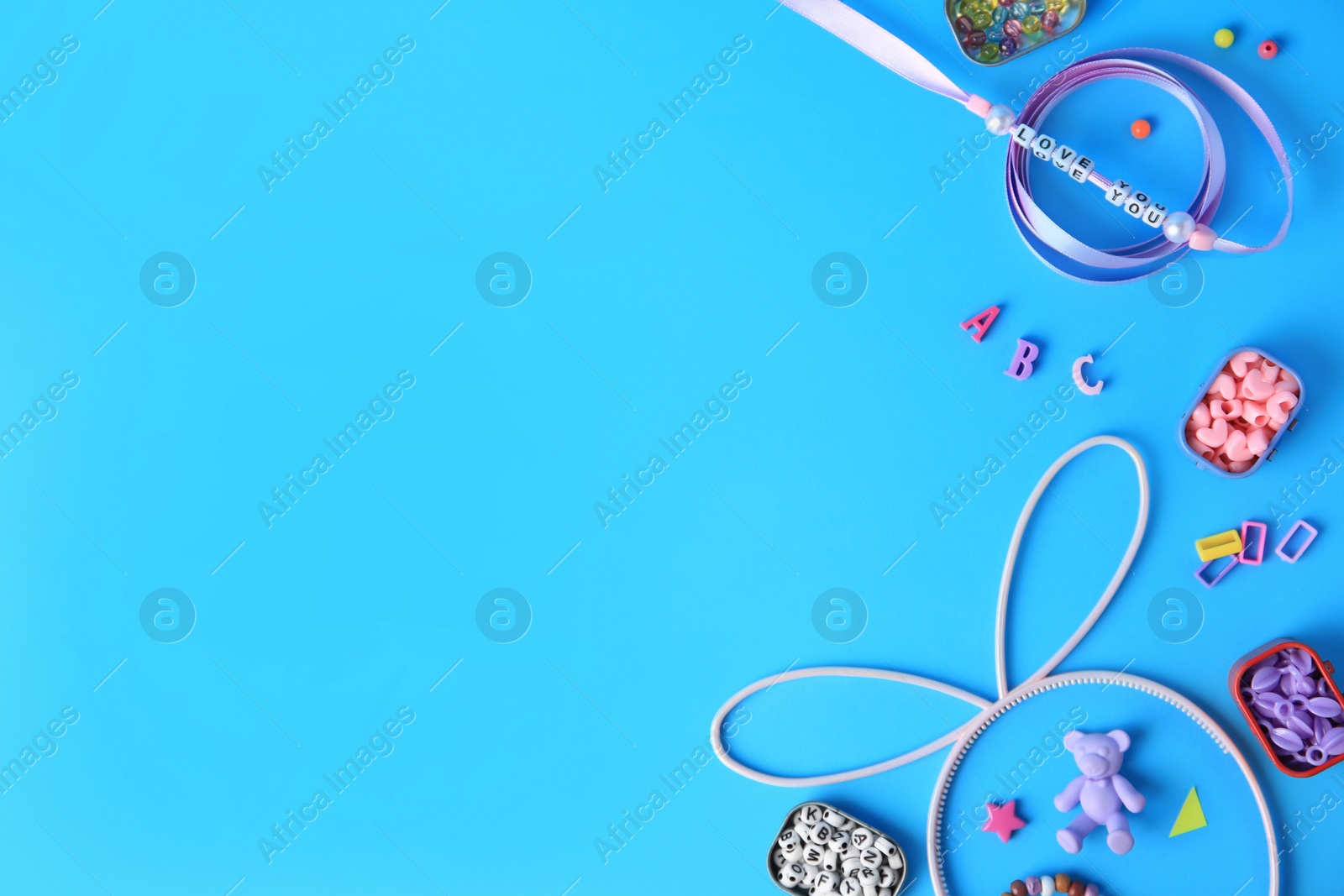 Photo of Kid`s handmade jewelry kit. Colorful beads, ribbon and supplies on light blue background, flat lay. Space for text