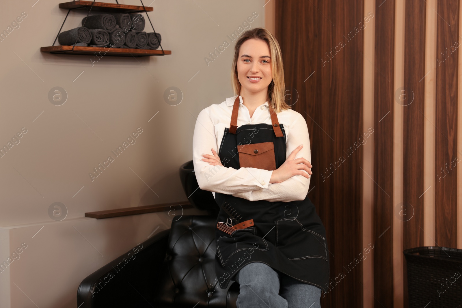 Photo of Portrait of professional hairdresser wearing apron in beauty salon