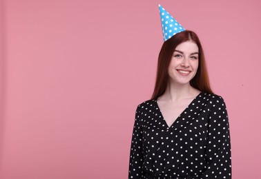 Photo of Happy woman in party hat on pink background, space for text