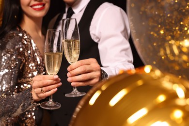 Photo of Couple with glassessparkling wine celebrating New Year on black background, closeup