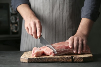 Man cutting fresh raw meat on table, closeup