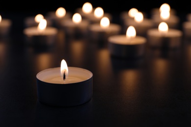 Photo of Burning candle on table in darkness, closeup with space for text. Funeral symbol